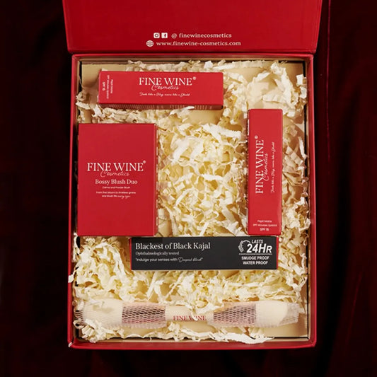 Open red cosmetics gift set box with multiple items in shredded filler