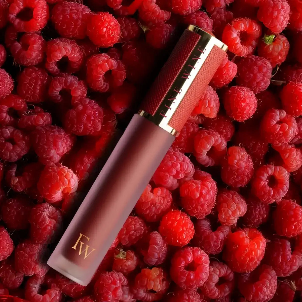 Mousse lipstick tube in mauve with red label, shown against raspberries