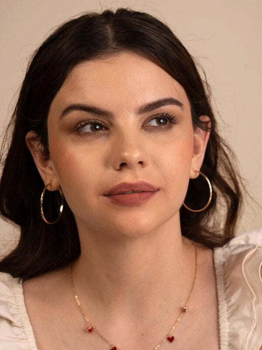 Model close-up with matte plum lipstick and gold hoop earrings