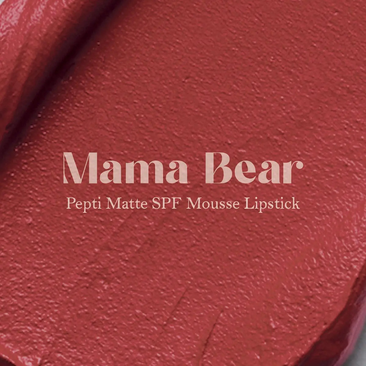 Matte lip mousse lipstick swatch, medium red-brown mauve on textured surface
