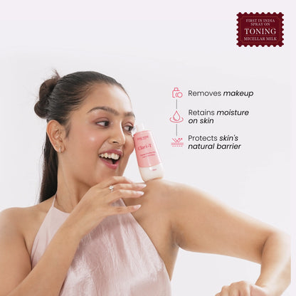 Woman holding Clari-T toning micellar milk bottle near her face.